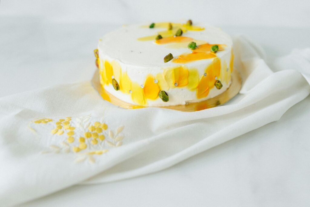 Beautifully decorated cake with pistachios and saffron accents on a white cloth.